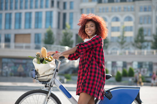 Cheerful curly woman feeling happy after buying foods - Photo, Image