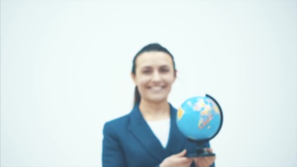 Happy teacher goes to the white background. In the hands of the globe. Close-up Slow video. - Materiał filmowy, wideo