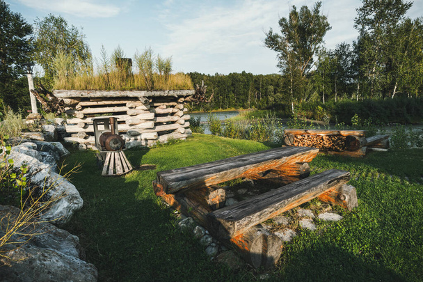 Malé dřevěné domky pro venkovní rekreaci se nacházejí na břehu řeky. Loviště. Tabulka klád v kempu pro turisty. Domácí a zahradní nábytek. agroturistika - Fotografie, Obrázek