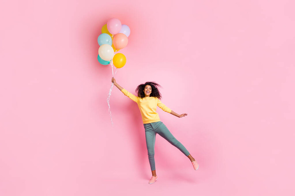 Full length photo of funky childish dreamy african girl hold many balons try fly in air enjoy holidays anniversary wear good look outfit sneakers isolated over pink color background - Foto, Imagem