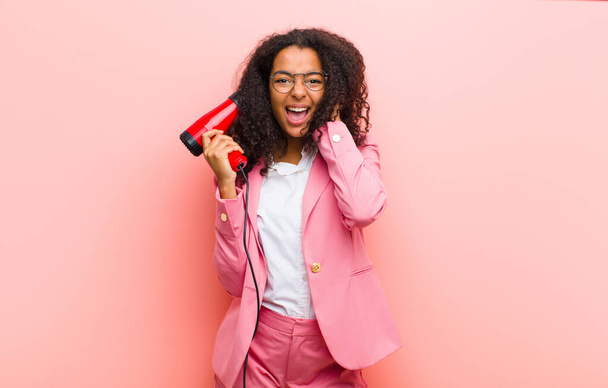 young black pretty woman with a hairdesser against pink wall background - Photo, image