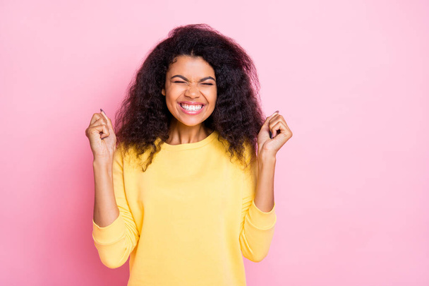 Portrait of positive cheerful lady african teen raise her fists wait for presents gift feel content enthusiastic wear lifestyle yellow jumer isolated over pink color background - Fotoğraf, Görsel