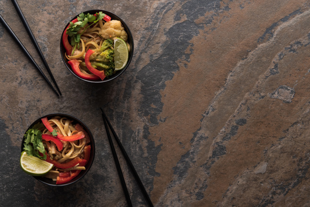 top view of tasty spicy thai noodles with chopsticks on stone surface - Valokuva, kuva