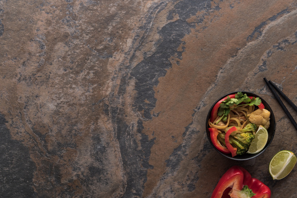 vista superior de macarrão tailandês picante saboroso com pauzinhos na superfície de pedra
 - Foto, Imagem