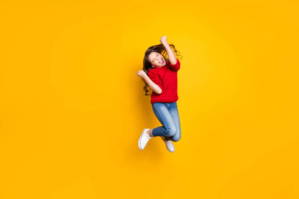 Full size photo of delighted crazy child wavy curly hair lucky kid win contest raise fists scream yeah wear stylish trendy pullover white sneakers isolated over yellow color background - Fotografie, Obrázek