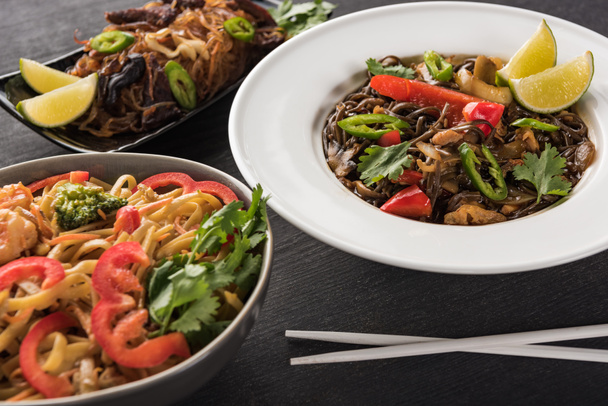 delicious spicy thai noodles near chopsticks on wooden grey surface - Valokuva, kuva