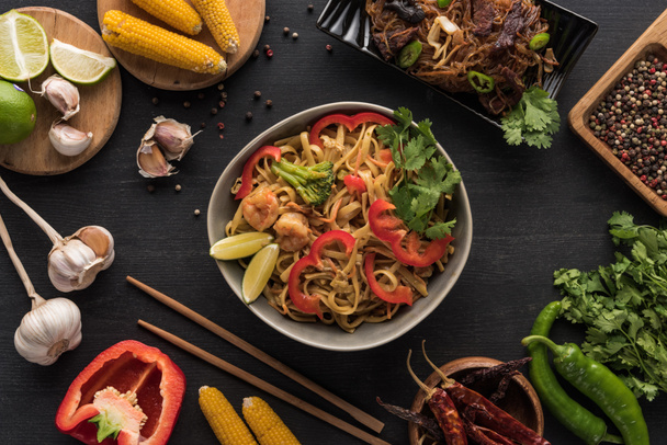 箸近くのおいしい辛い海鮮タイ麺と木の灰色の表面の新鮮な食材のトップビュー - 写真・画像