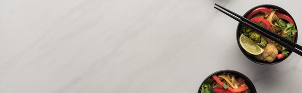 вид зверху смачна гостра тайська локшина з паличками на мармуровій сірій поверхні, панорамний знімок
 - Фото, зображення