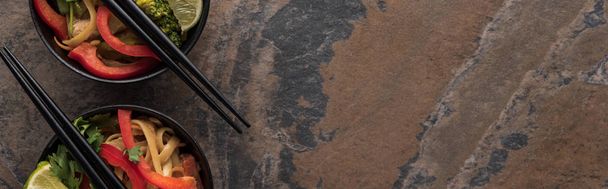 石の表面に箸が付いたボウルの中のタイ麺のトップビュー、パノラマショット - 写真・画像