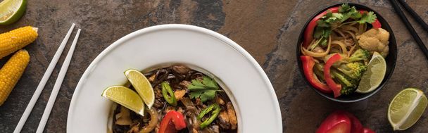 vista superior de macarrão tailandês com legumes e carne perto de pauzinhos, tiro panorâmico, tiro panorâmico
 - Foto, Imagem