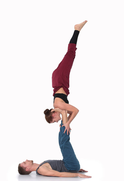 Young athletic couple practicing acroyoga. Balancing in pair. - Photo, Image