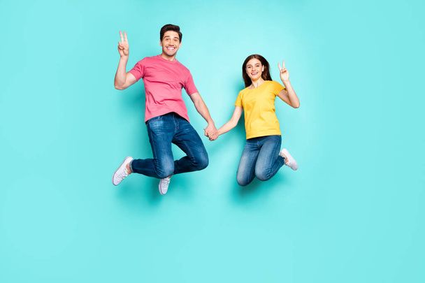 Full length body size view of nice attractive lovely cheerful cheery couple jumping up in air showing v-sign isolated over bright vivid shine vibrant green turquoise background - Photo, Image