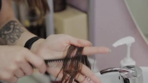 Κομμωτήριο κορίτσι χτένισμα βρεγμένα μαλλιά σε έναν πελάτη. - Πλάνα, βίντεο