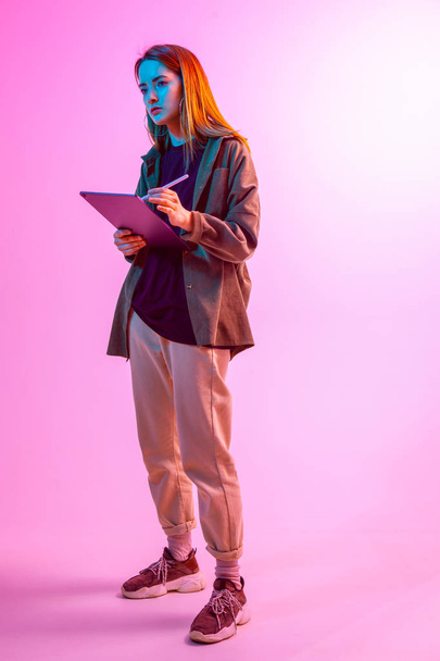 Modern Girl with laptop, tablet computer. Free creativity. Young blogger makes a Home office. Colored Neon light and background. - Foto, Imagem