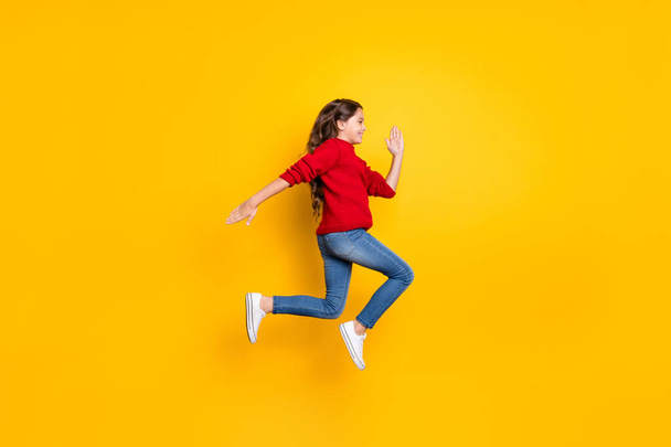 Full body profile side photo of positive cheerful model kid jump run fast speedy after black friday bargains wear red stylish pullover denim jeans white sneakers isolated over yellow color background - Foto, Bild