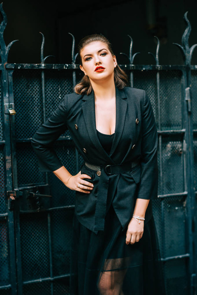 Siyah ceket ve etek giyen güzel bir kadının moda portresi, kırmızı dudaklı koyu renk makyaj. - Fotoğraf, Görsel