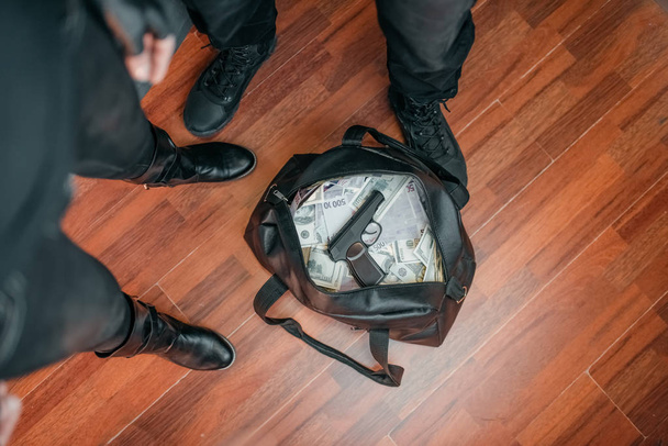 Ограбление банка, два грабителя в черной форме держат сумку с деньгами. Криминальная профессия, понятие кражи
 - Фото, изображение