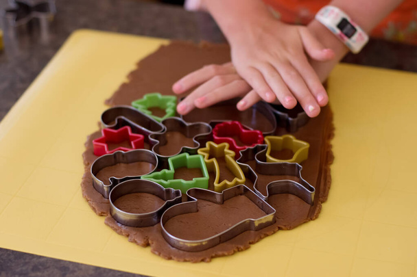 Маленькая девочка делает пряничное печенье на Рождество с различными кусачками для печенья
 - Фото, изображение