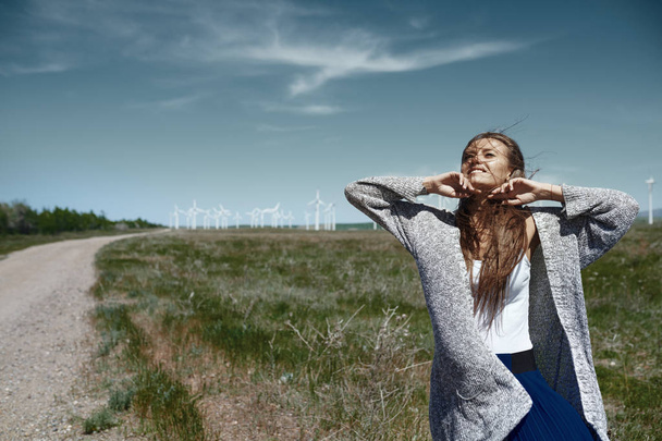 Женщина с длинными взъерошенными волосами рядом с ветряной турбиной с w
 - Фото, изображение