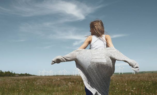 Woman with long tousled hair next to the wind turbine with the w - Foto, Bild