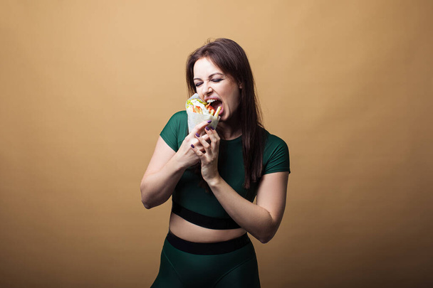 Primer plano de chica hambrienta con la boca abierta, sosteniendo y comiendo hamburguesa grande. Mujer bonita con hermoso peinado y labios rojos. Concepto de comida rápida
 - Foto, imagen