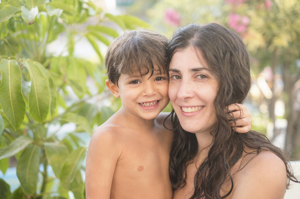Smiling mother and son in swimming pool summer day looking at camera - Foto, Imagem