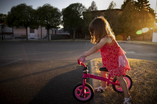 Menina andando de bicicleta ao pôr-do-sol
 - Foto, Imagem