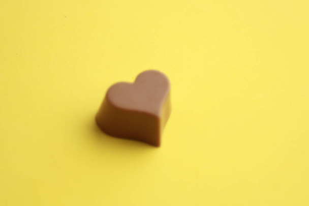 Chocolate bonbon with heart shape in color background - Fotó, kép