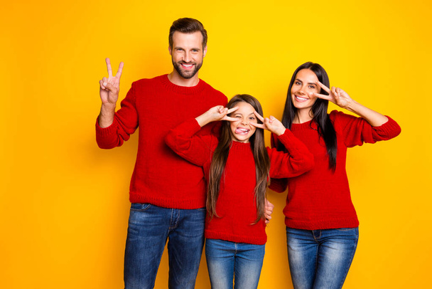 Photo of cute nice happy family day with daughter fooling sticking out showing v-sign tongue grimacing crazily wearing red sweater jeans denim isolated vivid color yellow background - Zdjęcie, obraz