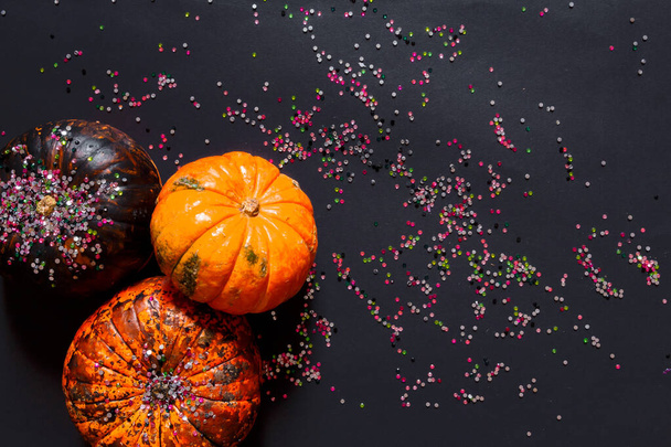 Creative composition flat view of pumpkins and tinsel Halloween glamor metallic trend on a black background with copy space - Foto, afbeelding