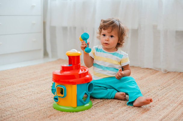 Baby spielt auf dem Fußboden im Zimmer in pädagogischem Plastikspielzeug. - Foto, Bild