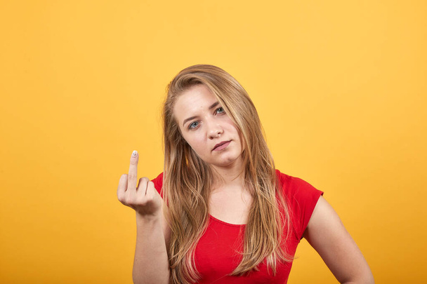 Jong blond meisje in rood t-shirt over geïsoleerde oranje achtergrond toont emoties - Foto, afbeelding