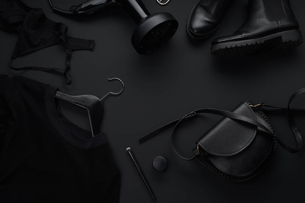 Black monochromatic clothes and accessories with beauty equipment on dark background. Black friday sale concept  - Photo, Image