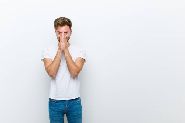 young man looking happy, cheerful, lucky and surprised covering mouth with both hands against white background - Foto, immagini