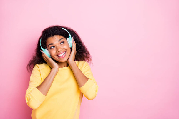 Portrait of cheerful cute african girl listen music song radio on her earphones enjoy break pause free time wear yellow lifestyle jumper pullover isolated over pastel color background - Foto, immagini