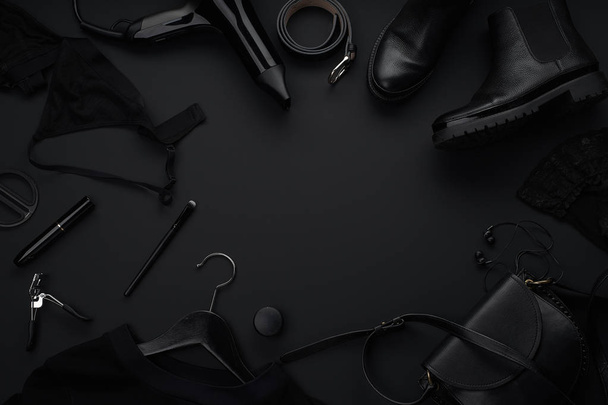 Black monochromatic clothes and accessories with beauty equipment on dark background. Black friday sale concept  - Photo, image