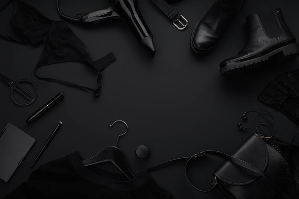 Black monochromatic clothes and accessories with beauty equipment on dark background. Black friday sale concept  - Фото, зображення