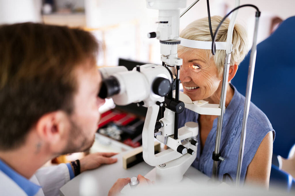 Older lady taking an eyesight test examination at an optician clinic - Photo, Image