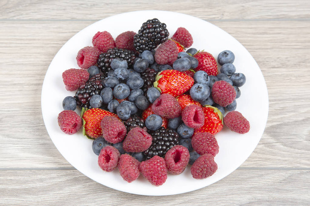 Blackberry, raspberry blueberry and strawberry on a white plate. - Foto, immagini