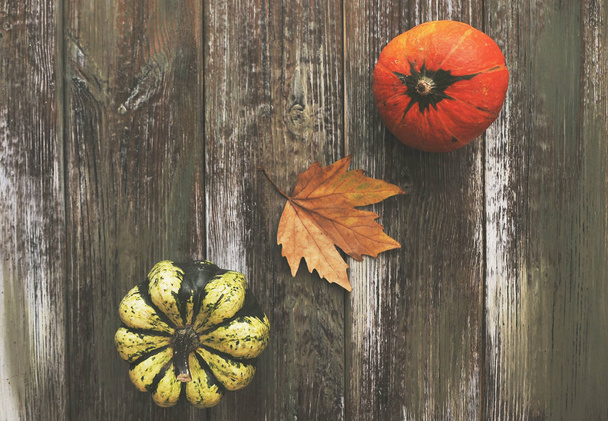 Herfst achtergrond. Pompoenen, appels, noten, bladeren, kopjes en trui op houten ondergrond. - Foto, afbeelding