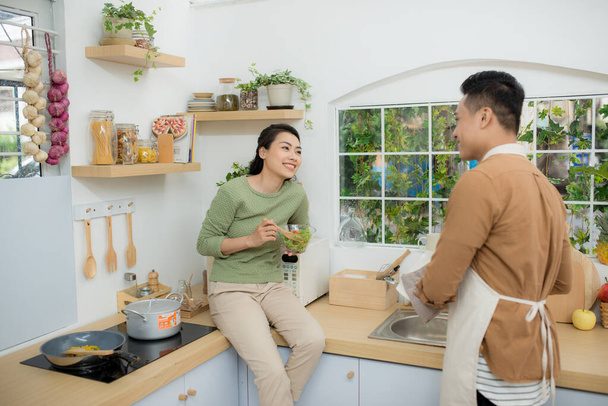 Asian couple eating breakfast early in the morning in the kitchen and having a good time. - Foto, Imagen