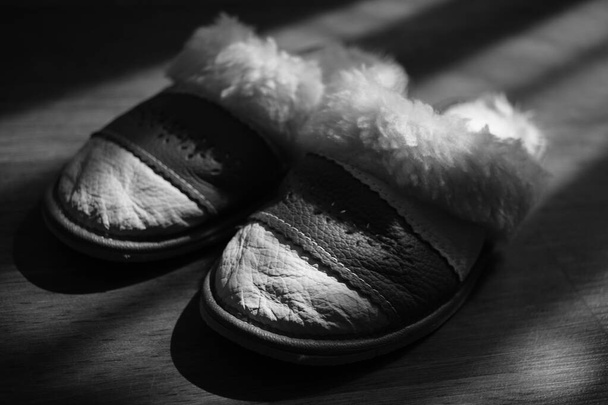 Pantofole da donna con una pelle di pecora su un pavimento di legno. BW foto
. - Foto, immagini