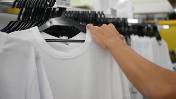 Male customer looking for T-shirts in store - Footage, Video