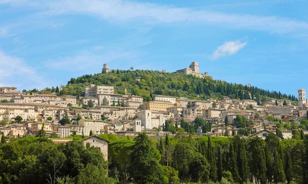 Panoramiczny widok na zabytkowe miasto Asyż w piękny słoneczny dzień z błękitnym niebem i chmurami w lecie, Umbria, Włochy. - Zdjęcie, obraz