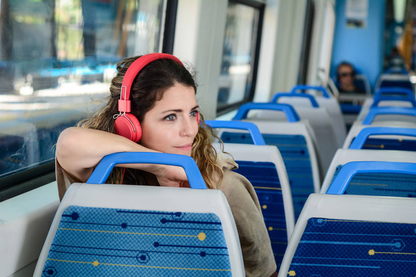 Beautiful young woman listening to music in a train. - Photo, image
