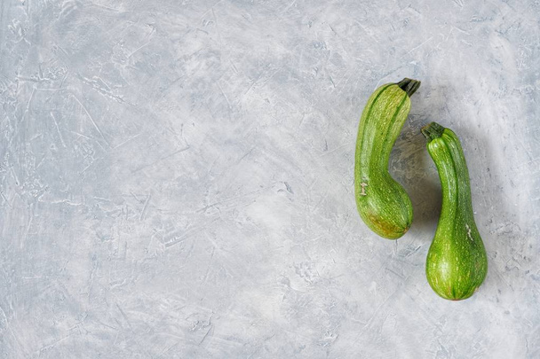 Two spoiled zucchini on a gray background. Ugly food concept, organic vegetables. Close-up, selective focus.Copy space for text. - Foto, imagen