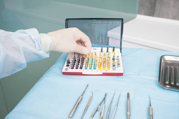 The dentists hand takes the endodontic obstructive dental equipment in the dentists office - 写真・画像