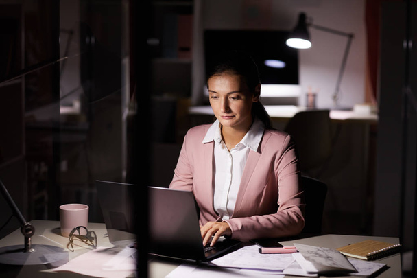 Młoda bizneswoman koncentrująca się na pracy w biurze i pisaniu na laptopie późnym wieczorem w biurze  - Zdjęcie, obraz