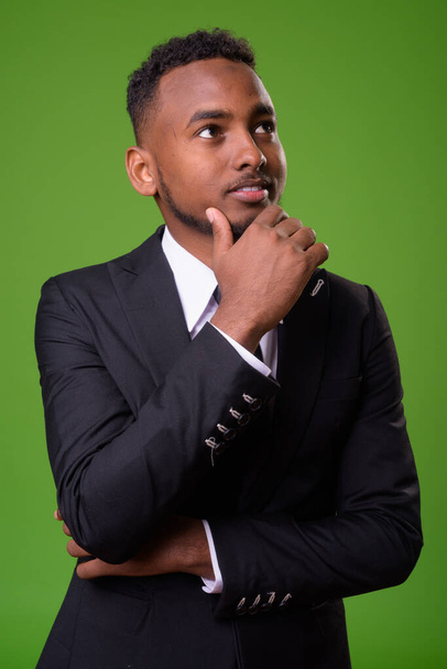 Молодий красивий африканських бізнесмен на зеленому тлі - Фото, зображення