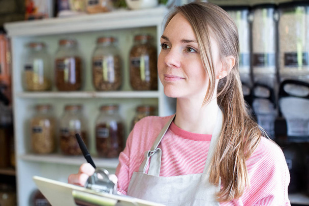 Vrouwelijke eigenaar van duurzame plastic gratis kruidenierswinkel Checking  - Foto, afbeelding